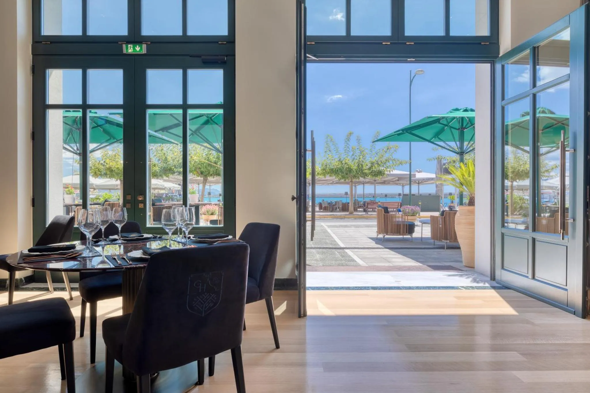 Une salle à manger lumineuse s'ouvre sur une terrasse ombragée avec vue sur la mer.