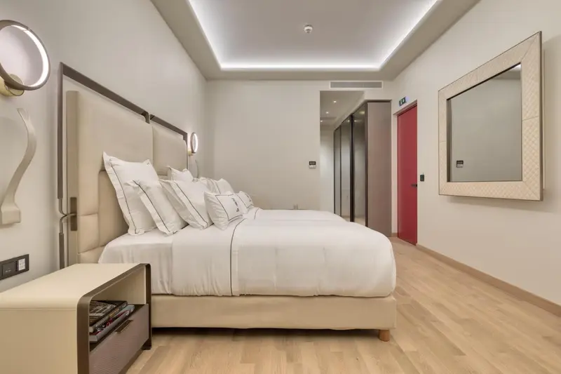Une chambre lumineuse avec un grand lit recouvert de coussins blancs.