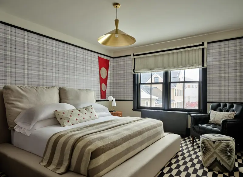 Une chambre lumineuse avec un grand lit et un fauteuil près d'une fenêtre.