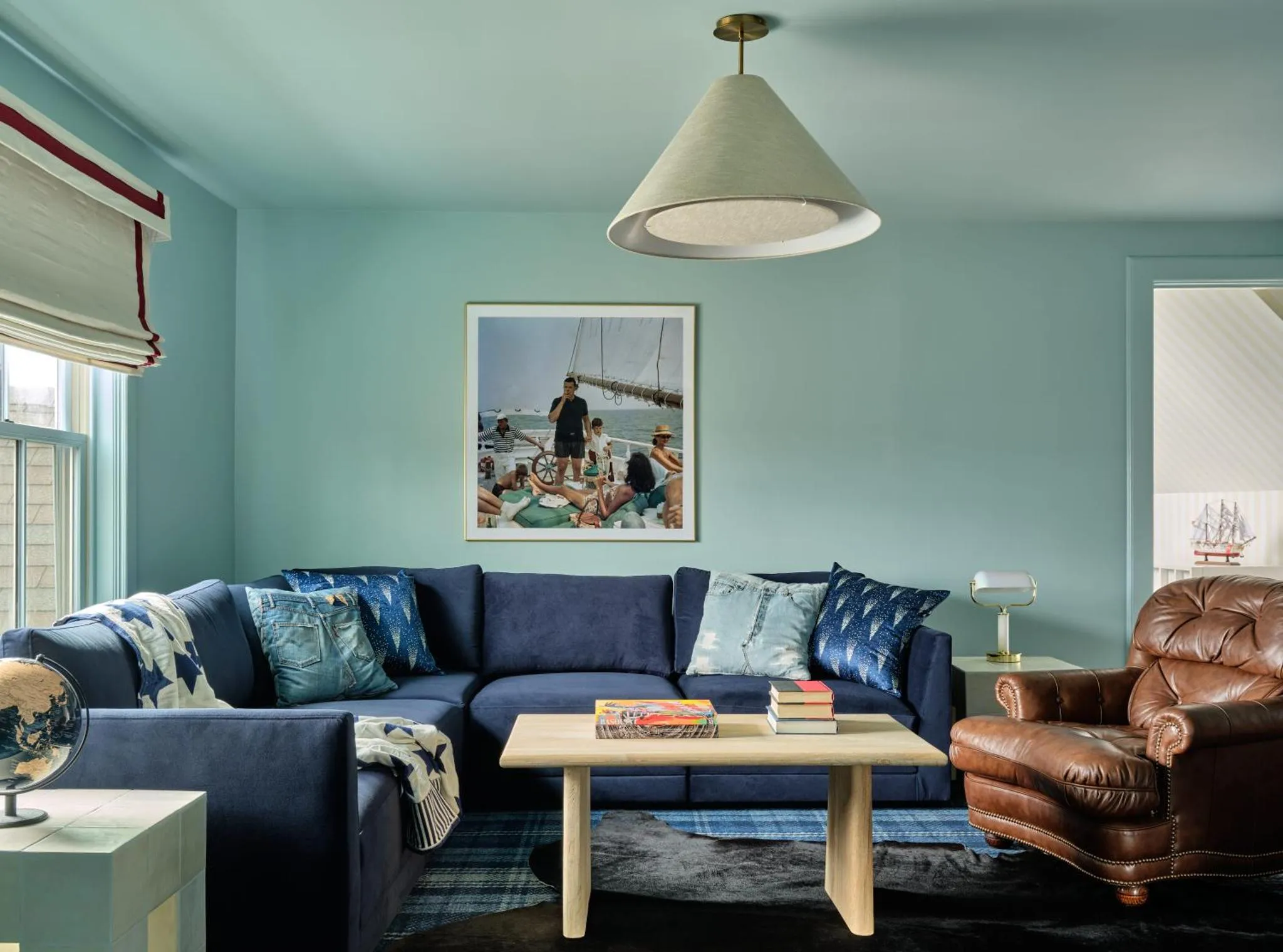 Un canapé bleu foncé et un fauteuil en cuir marron sont disposés dans un espace de détente lumineux.