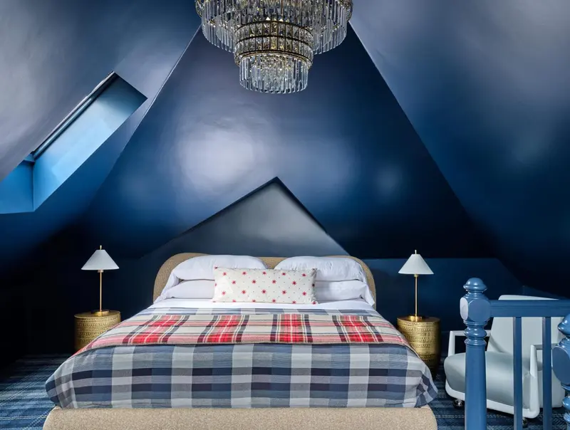 Une chambre mansardée avec un lit recouvert d'une courtepointe à carreaux.