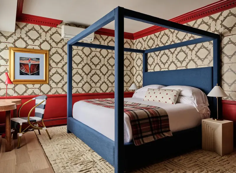 Une chambre à coucher avec un lit à baldaquin bleu et des motifs muraux.