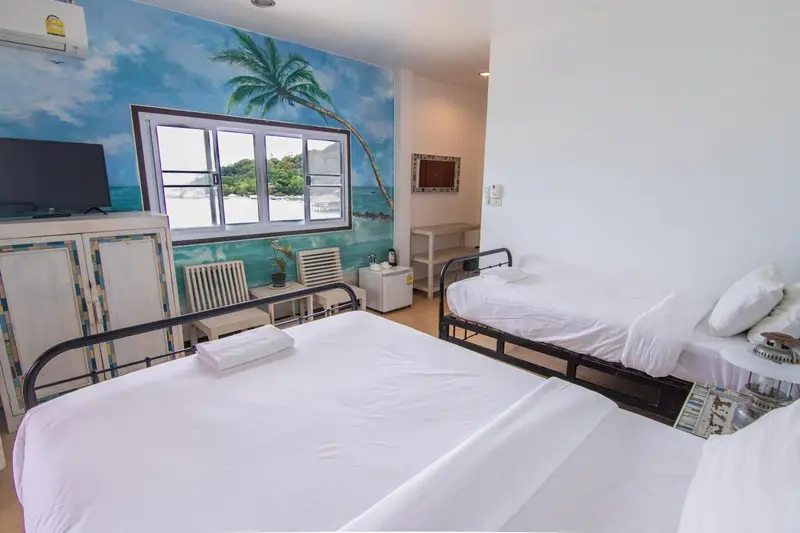 Une chambre lumineuse avec deux lits simples et une décoration murale évoquant une vue sur la mer.