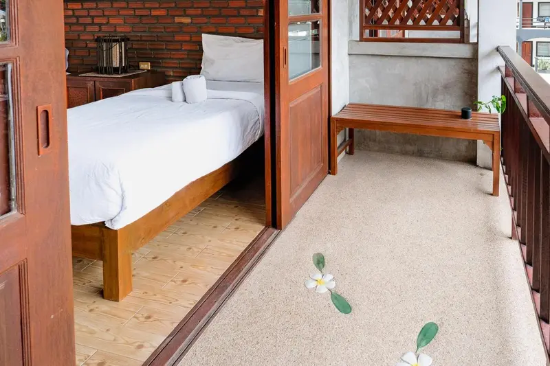 Une chambre lumineuse s'ouvre sur une terrasse en bois.