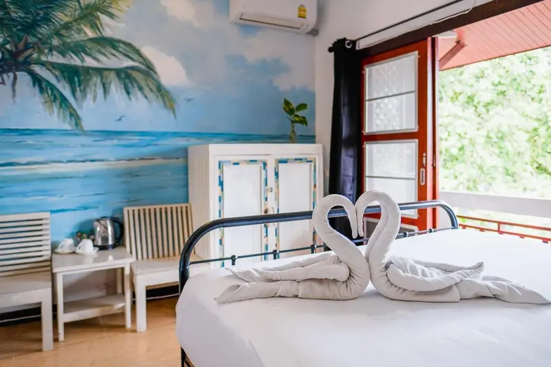 Une chambre lumineuse avec un lit décoré de serviettes en forme de cygnes.