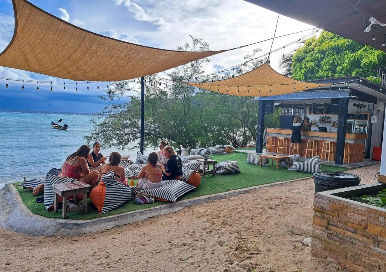 Des personnes sont assises sur des coussins devant un bar en bord de mer.