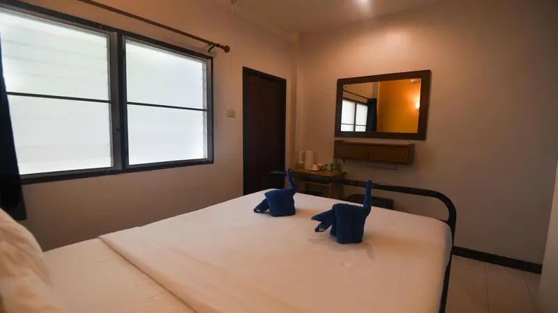 Une chambre lumineuse avec un lit fait et un miroir mural.