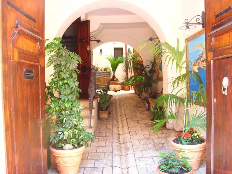 Une arche mène à une cour intérieure ornée de plantes et de pots de fleurs.