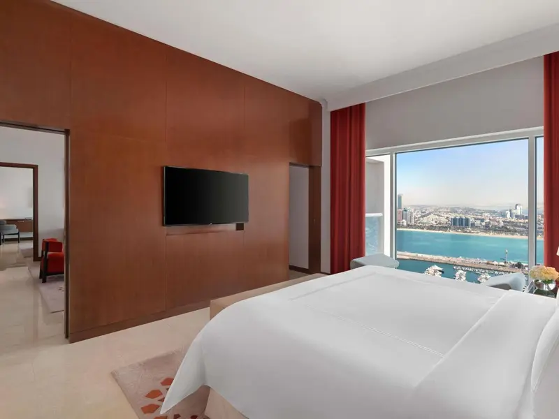Chambre lumineuse avec un grand lit et une vue sur la mer.