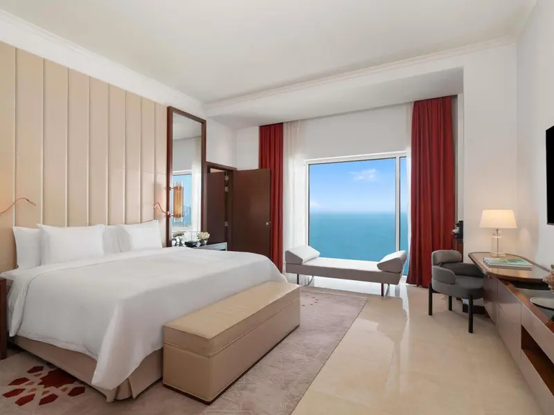 Chambre lumineuse avec un grand lit et une vue sur la mer.