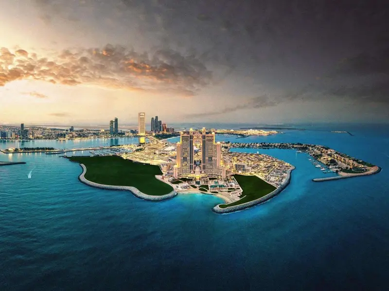 Vue aérienne d'un complexe hôtelier sur une île artificielle au coucher du soleil.