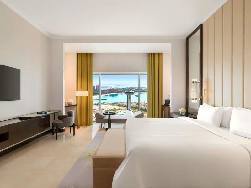 Chambre lumineuse avec un grand lit et une vue sur la mer.