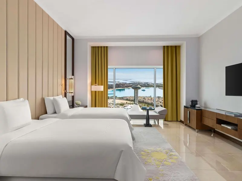 Une chambre lumineuse avec deux lits simples et une vue sur la mer.