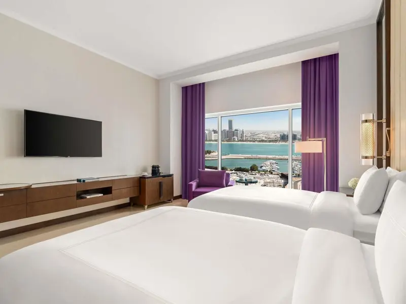 Chambre d'hôtel lumineuse avec vue sur la mer et la ville.