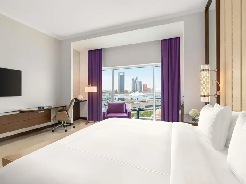 Une chambre lumineuse avec un grand lit et une vue sur la ville.