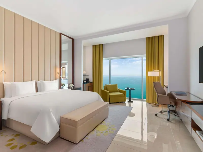 Chambre lumineuse avec un grand lit et une vue sur la mer.