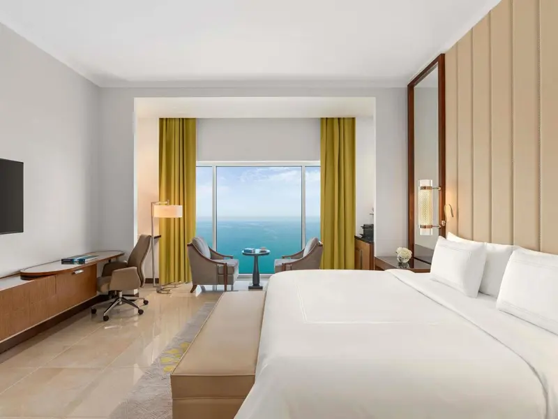 Chambre lumineuse avec un grand lit et une vue sur la mer.