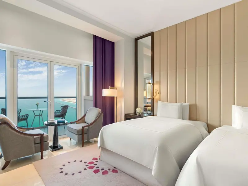Chambre lumineuse avec vue sur la mer depuis un balcon.