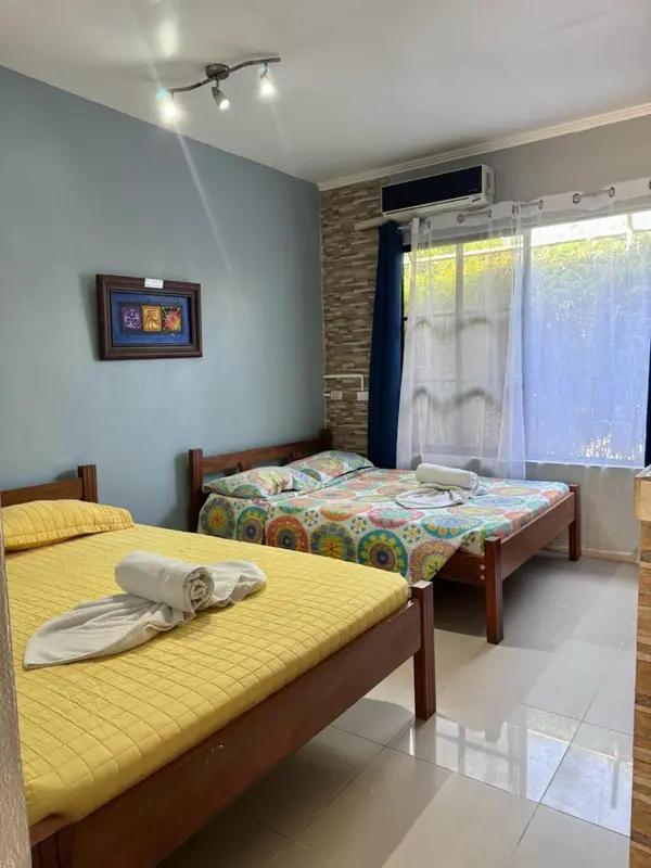 Une chambre lumineuse avec deux lits simples et une décoration colorée.