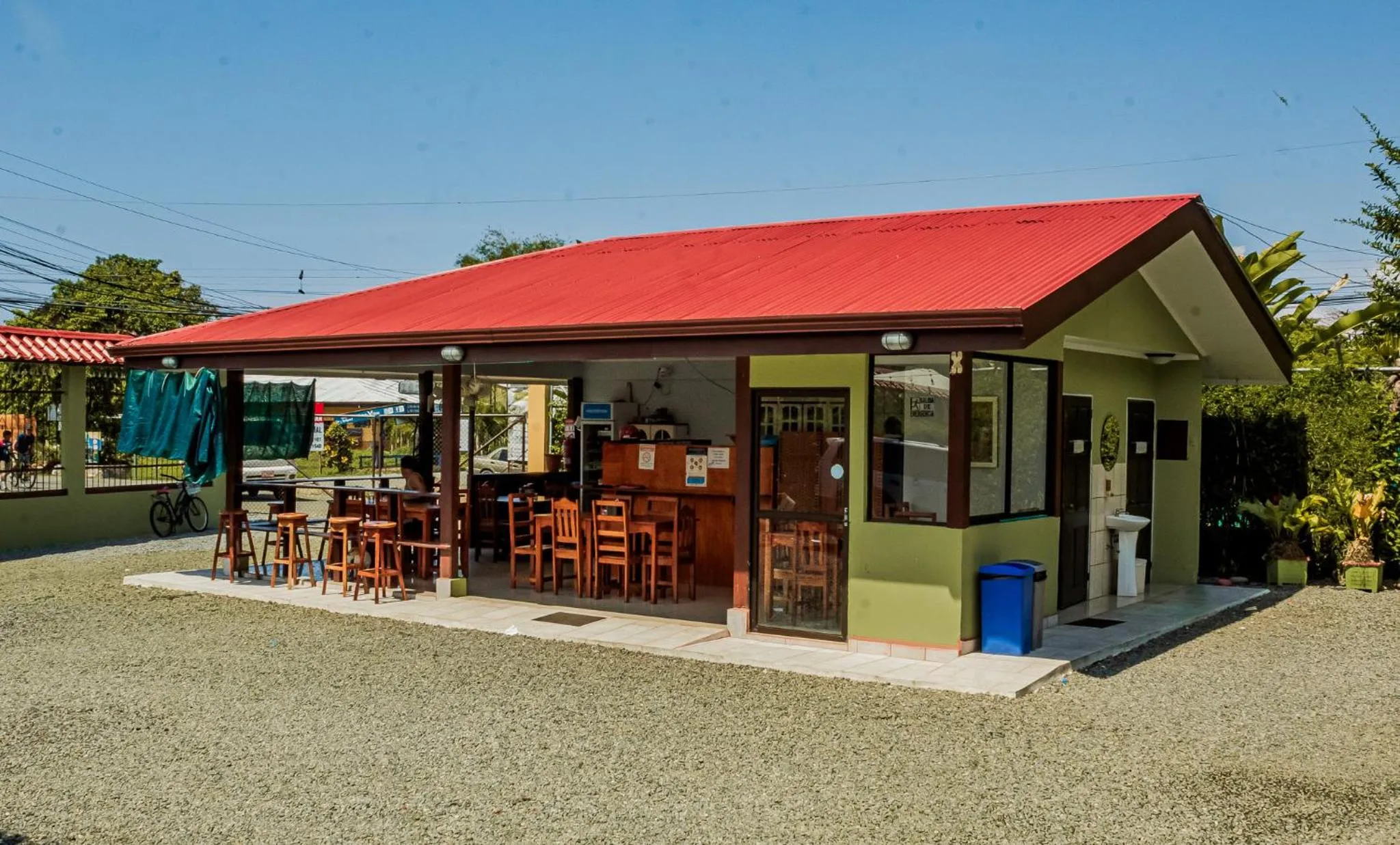 Un bar ouvert sur une terrasse en gravier avec des tabourets et une zone de service.