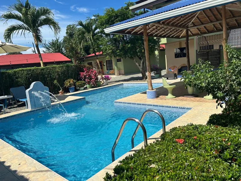 Une piscine rectangulaire avec une cascade et des transats en bordure.