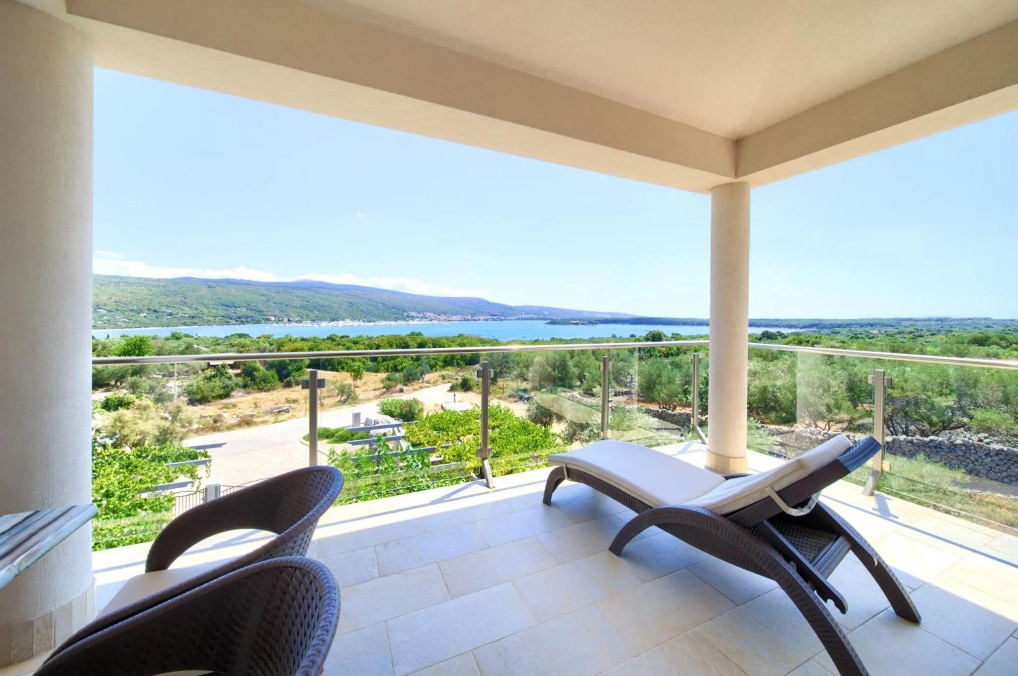 Terrasse avec mobilier d'extérieur et vue sur la mer et la végétation.