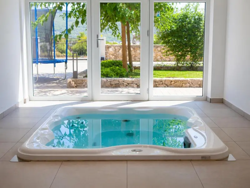 Un jacuzzi intérieur avec vue sur un jardin et une balançoire.