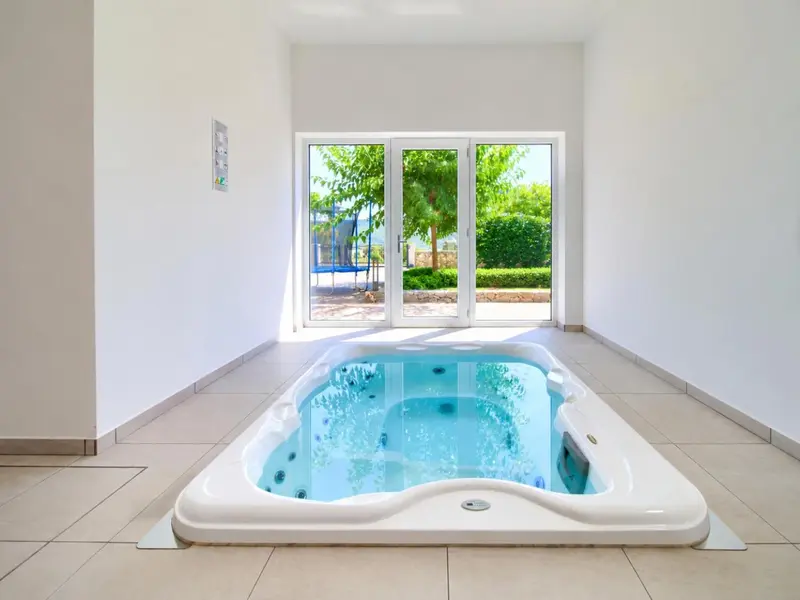 Un jacuzzi intérieur donne sur une terrasse ensoleillée.