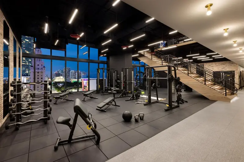 Une salle de sport lumineuse avec des équipements de musculation et une vue sur la ville.