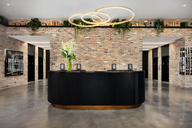 Un comptoir d'accueil moderne avec un mur de briques et des plantes vertes.