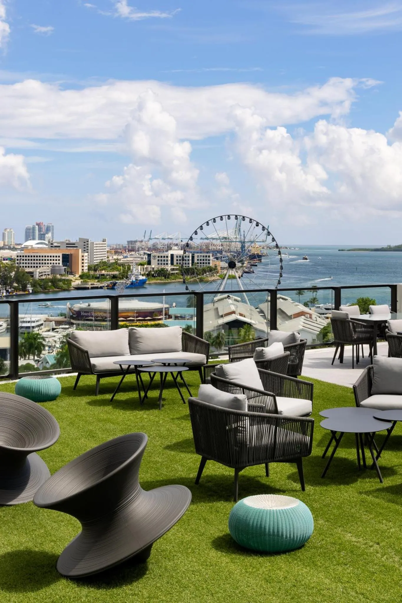 Terrasse aménagée avec mobilier de jardin et vue sur la mer et la ville.