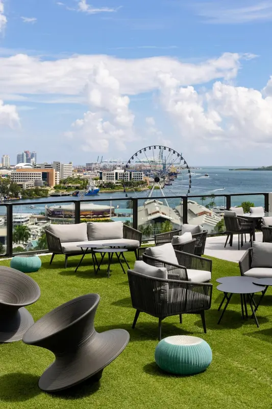 Terrasse aménagée avec mobilier de jardin et vue sur la mer et la ville.