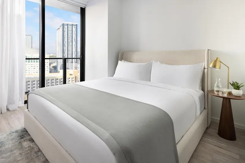 Une chambre lumineuse avec un grand lit et une vue sur la ville.
