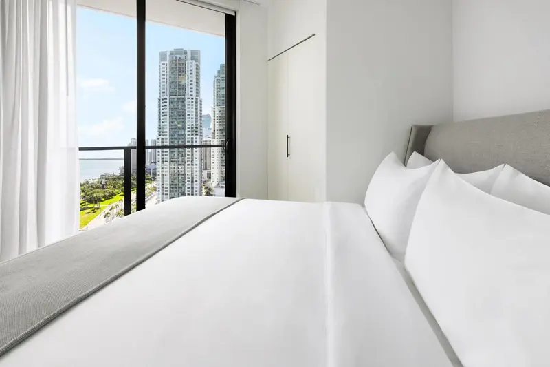 Une chambre lumineuse avec un grand lit et une vue sur la ville.