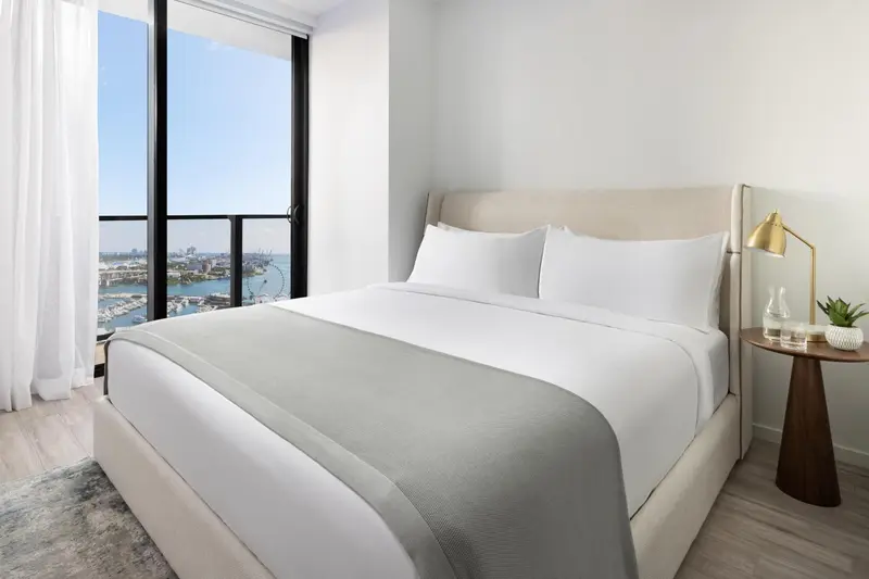 Une chambre lumineuse avec un grand lit et une vue sur la ville.