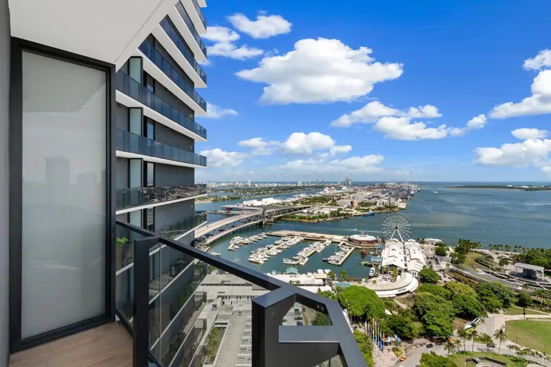 Vue panoramique sur la ville et la mer depuis un balcon.