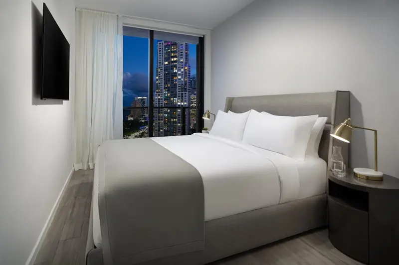 Une chambre moderne avec un grand lit et une vue nocturne sur la ville.