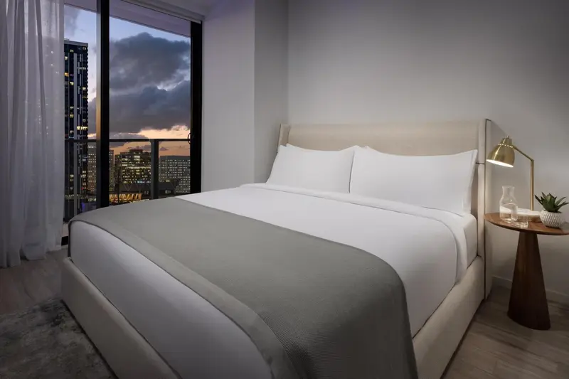 Une chambre moderne avec un grand lit et une vue sur la ville illuminée.