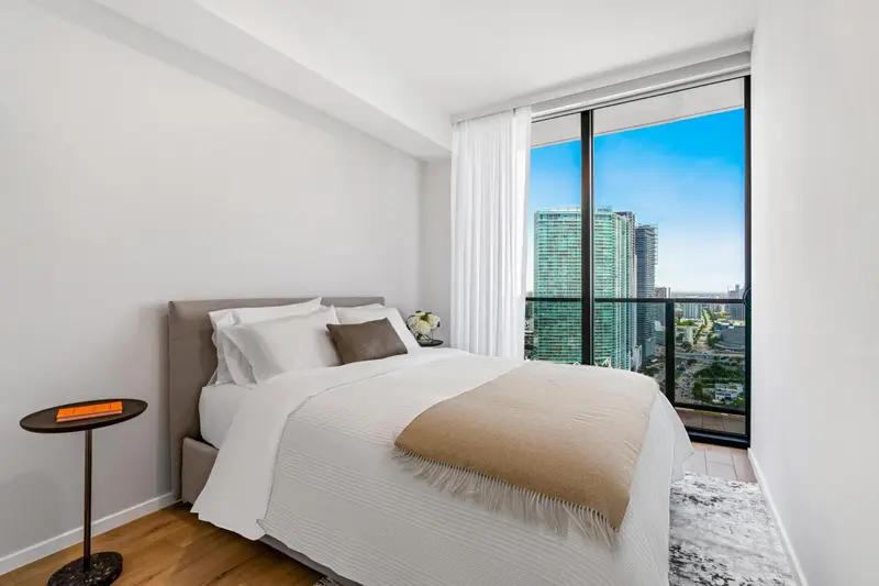 Une chambre lumineuse avec un grand lit et une vue sur la ville.
