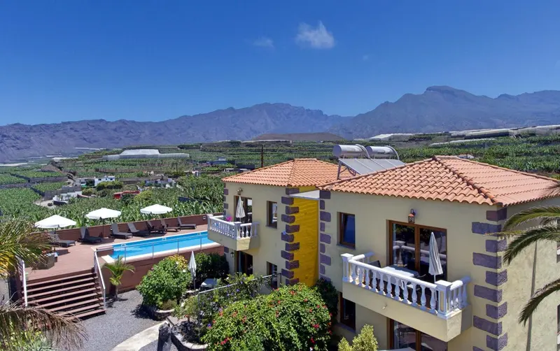Bâtiment jaune avec piscine et vue sur les montagnes.