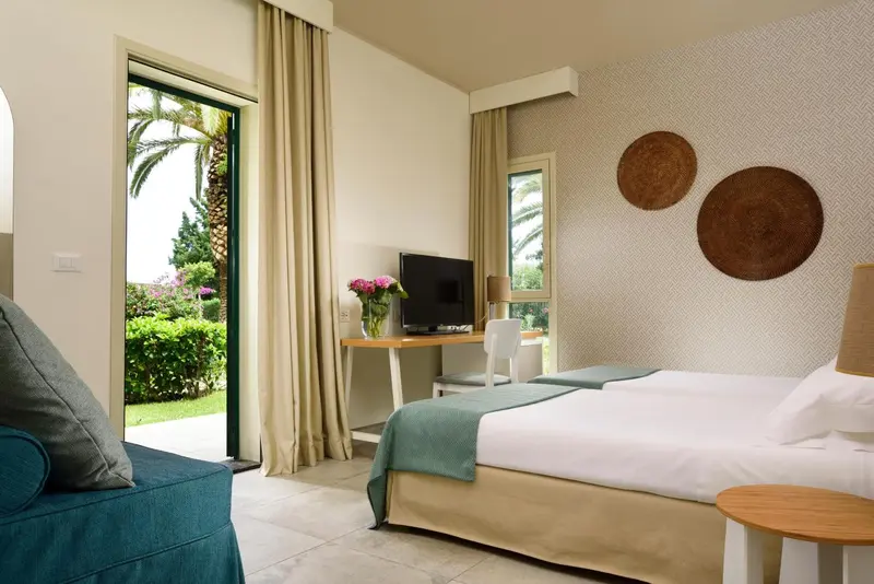 Une chambre lumineuse avec un lit et un coin salon donnant sur un jardin.