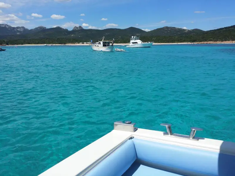 Vue sur une plage turquoise et des bateaux amarrés dans une baie ensoleillée.