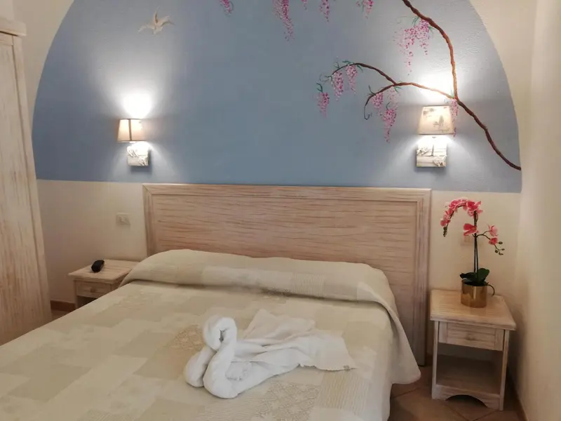 Une chambre lumineuse avec un lit recouvert d'une couverture blanche et de serviettes en forme de cygnes.