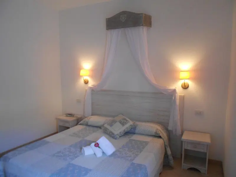 Une chambre lumineuse avec un grand lit recouvert d'une courtepointe.