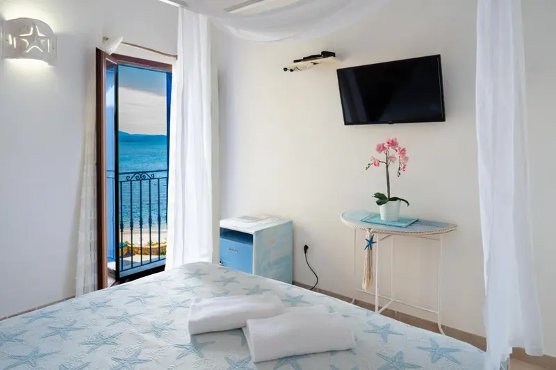 Chambre lumineuse avec un lit décoré et vue sur la mer.