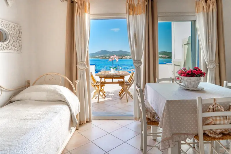 Une chambre lumineuse s'ouvre sur une terrasse avec vue sur la mer.