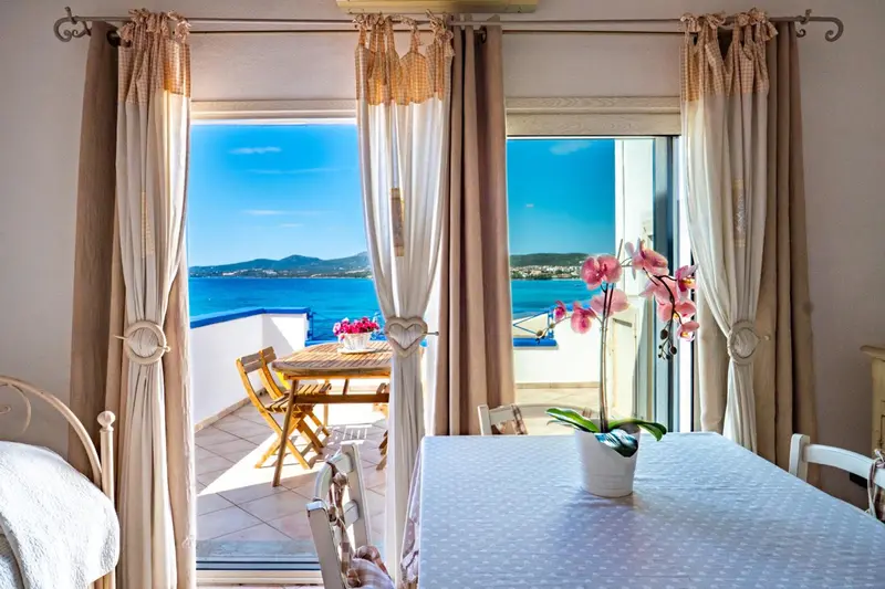 Vue sur la mer depuis une terrasse avec table et fleurs.