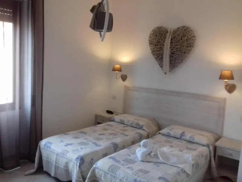 Une chambre lumineuse avec deux lits simples et une décoration murale en forme de cœur.