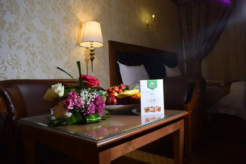 Une chambre d'hôtel avec un arrangement floral et un plateau de fruits sur une table basse.