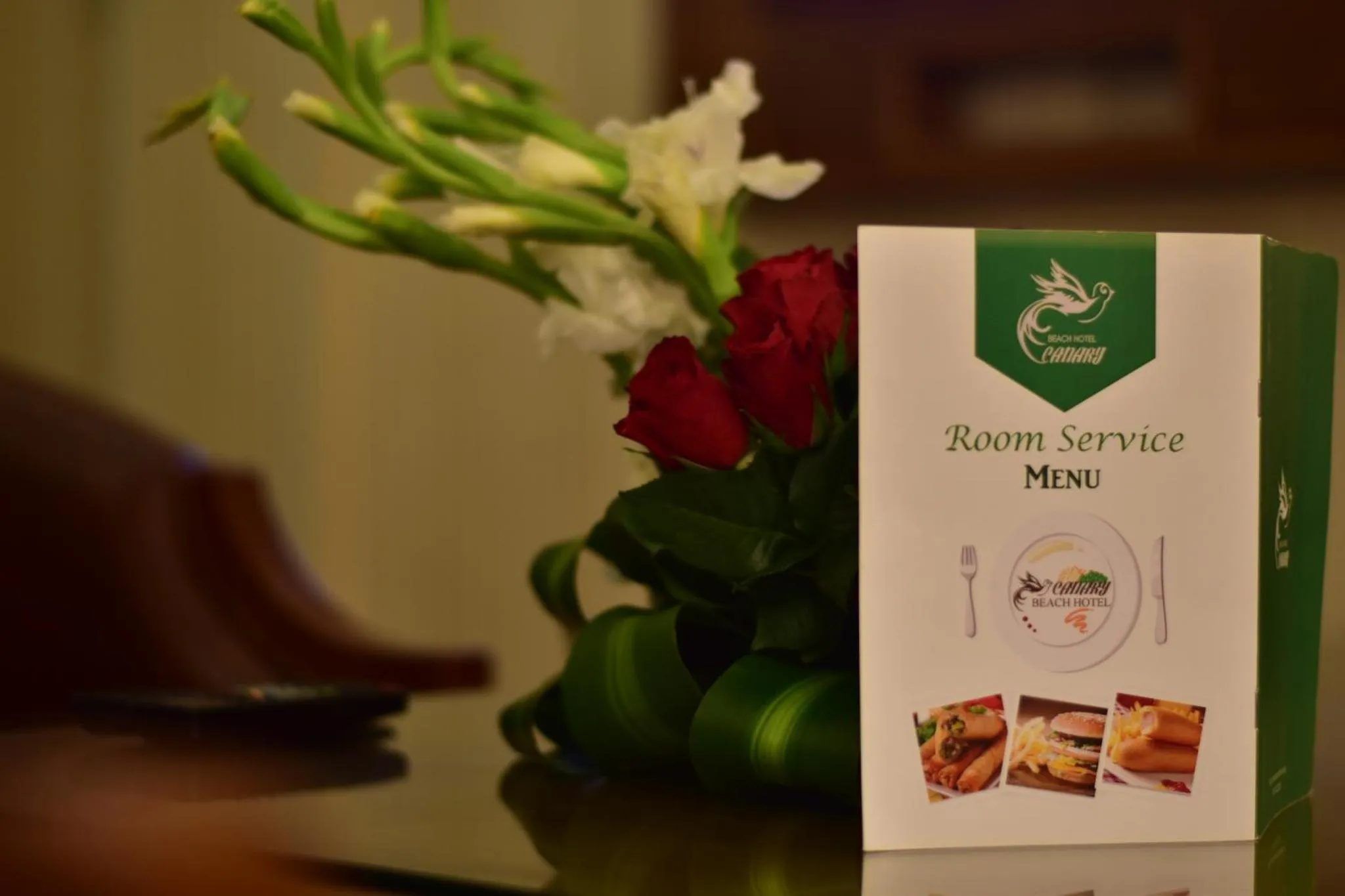 Un bouquet de fleurs et un menu de service en chambre sont posés sur une surface sombre.
